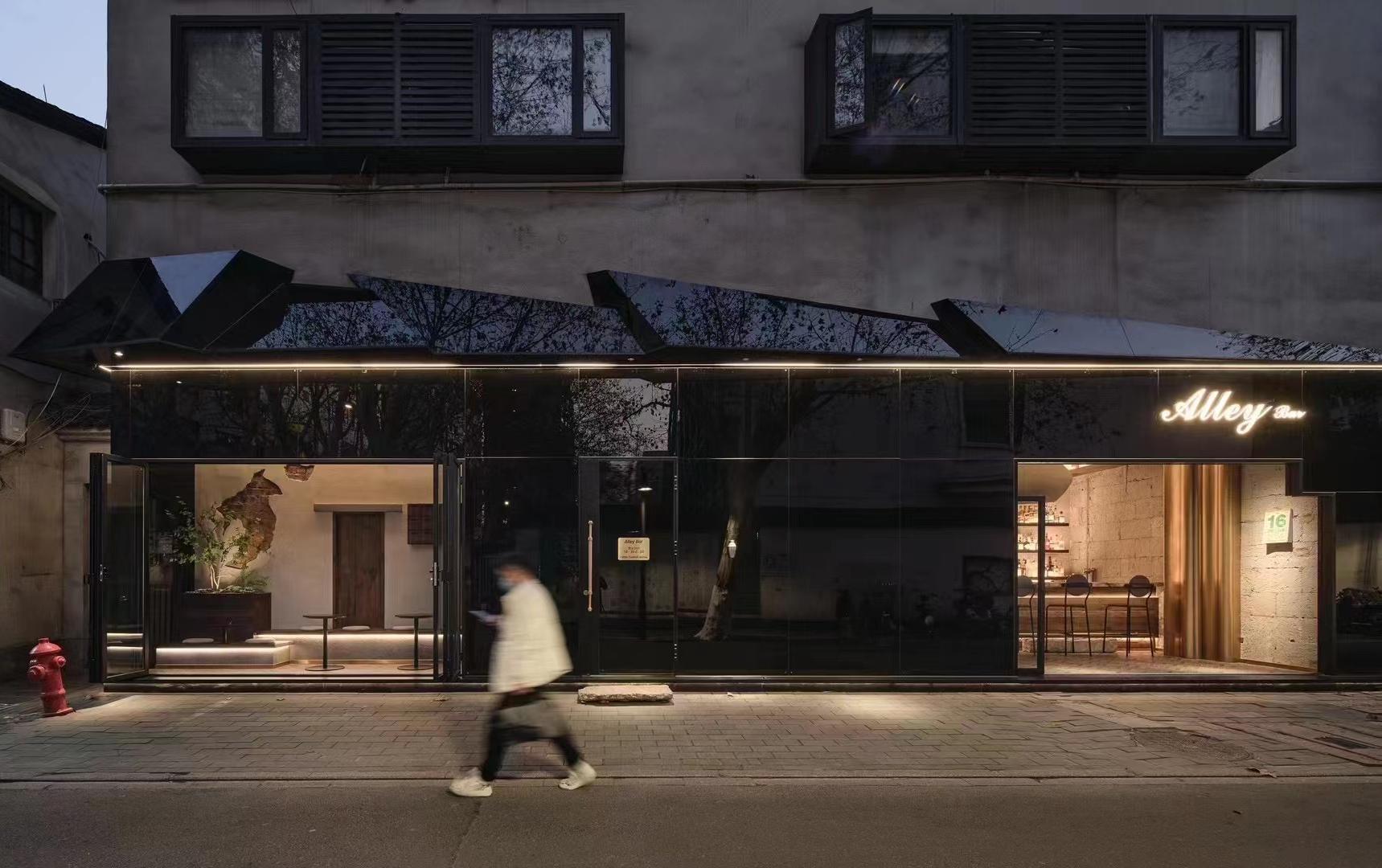 Night view of urban bar exterior with black metal storefront and signage