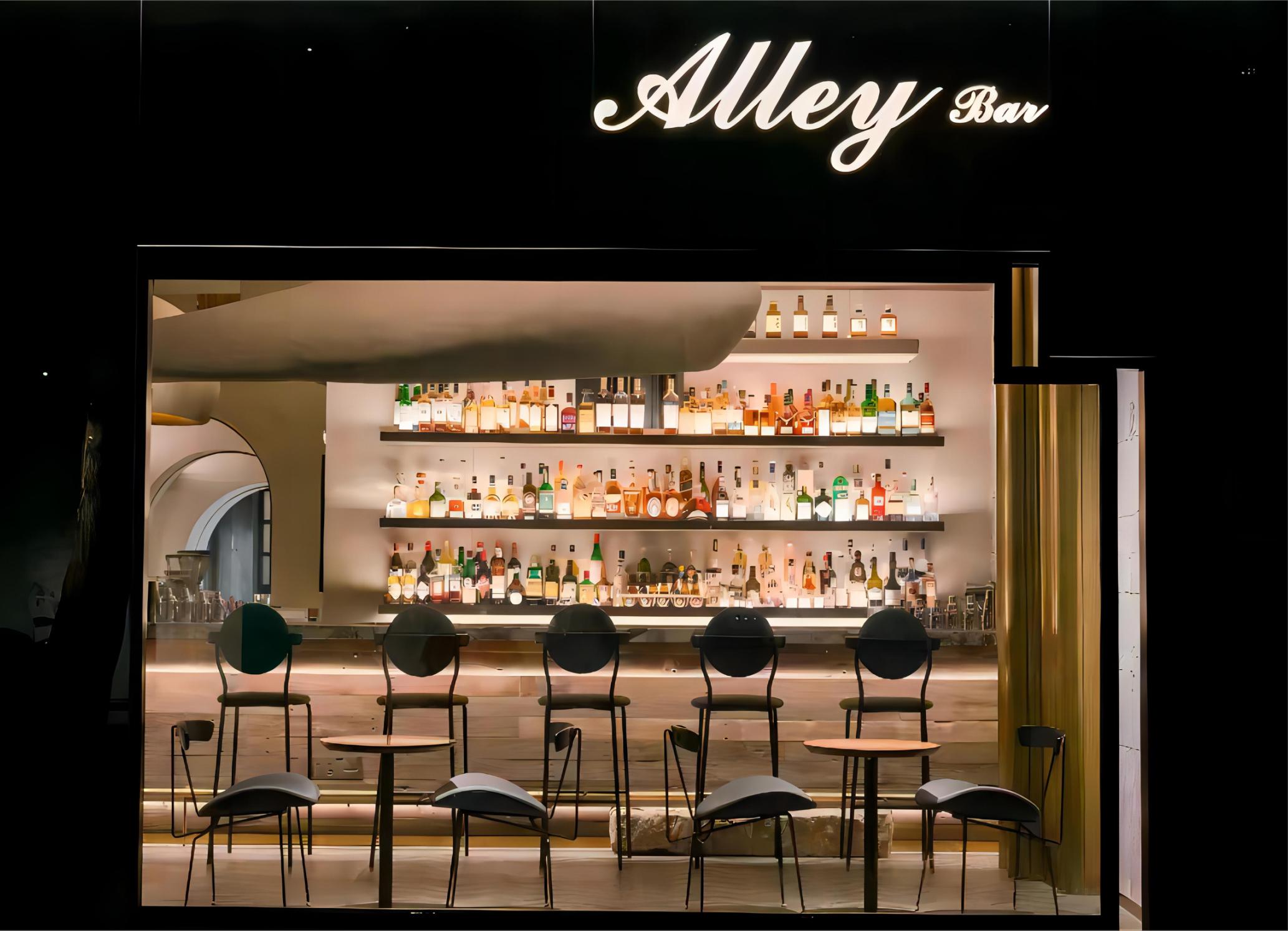 Bar interior with illuminated bottle display and compact counter layout