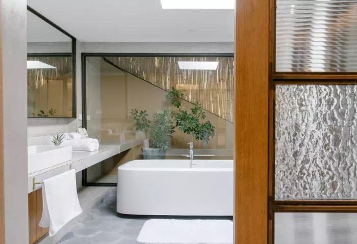 Compact boutique guest room bathroom with glass partition and wood detail