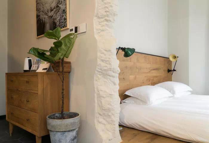 Small hotel bedroom corner with wood furniture and natural wall texture