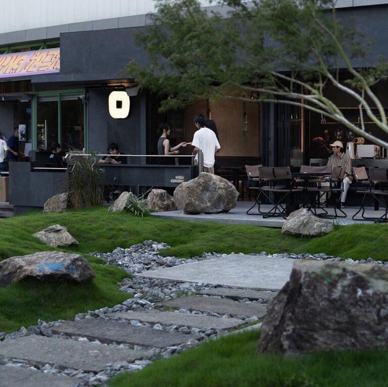Dark timber restaurant exterior with courtyard garden and warm entrance lighting
