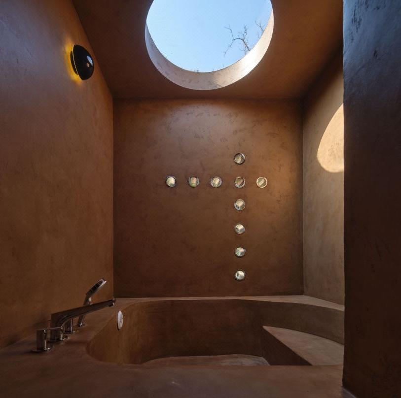 Boutique resort bathroom with circular skylight and textured walls