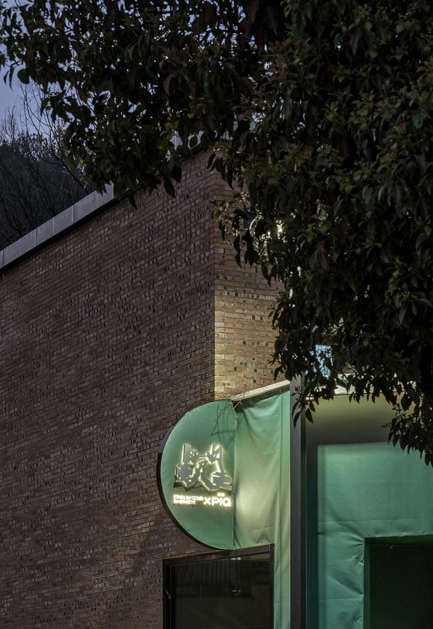 Green commercial showroom facade detail with curved entrance and lighting