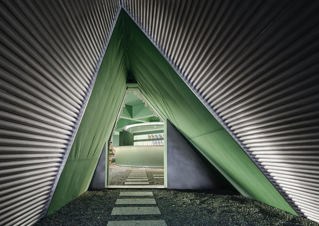 Triangular green storefront feature with metal ceiling and glass block wall