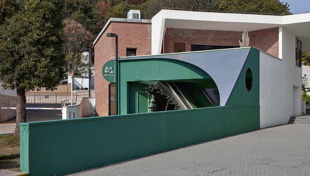 Compact green commercial building with curved facade and street entrance