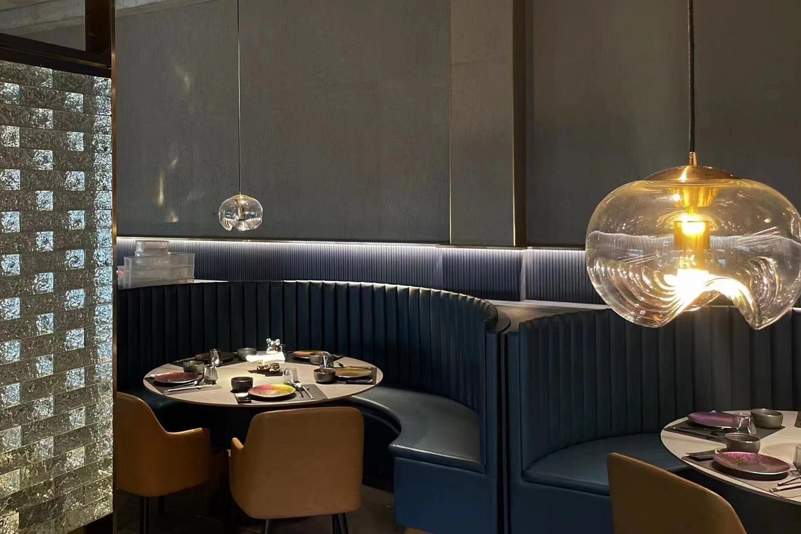 Garden restaurant dining room with pendant light and curved booth seating