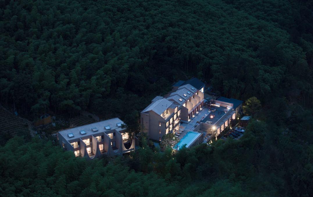 Night view of mountain resort building integrated with forest landscape