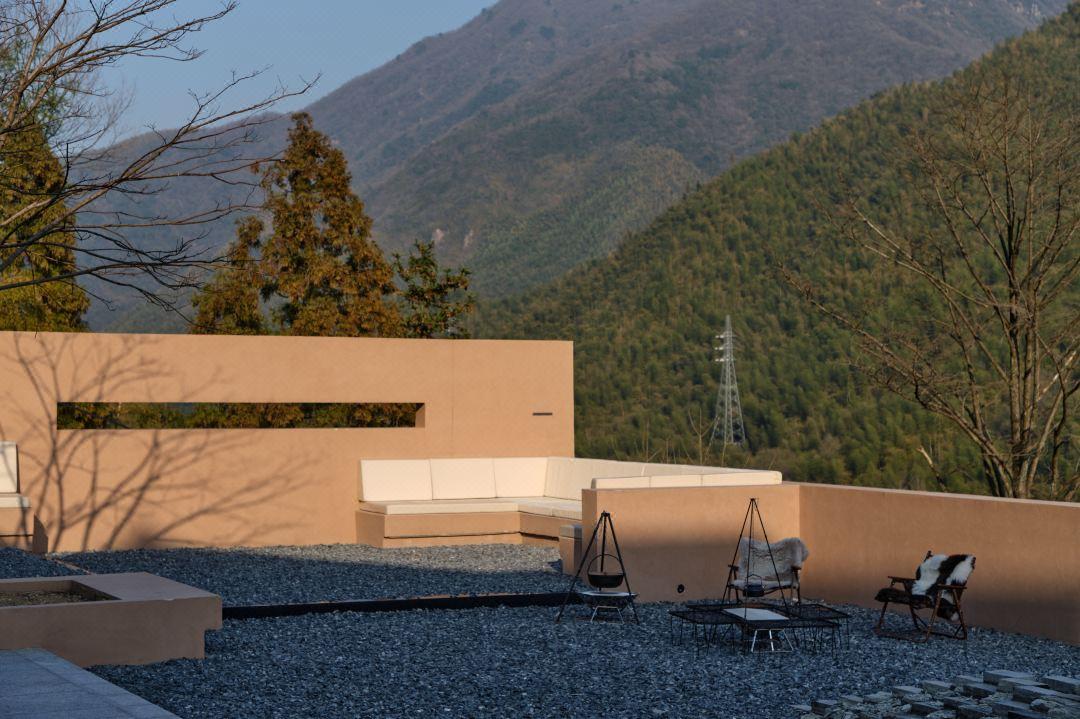 Modern resort terrace facade with mountain backdrop and outdoor seating