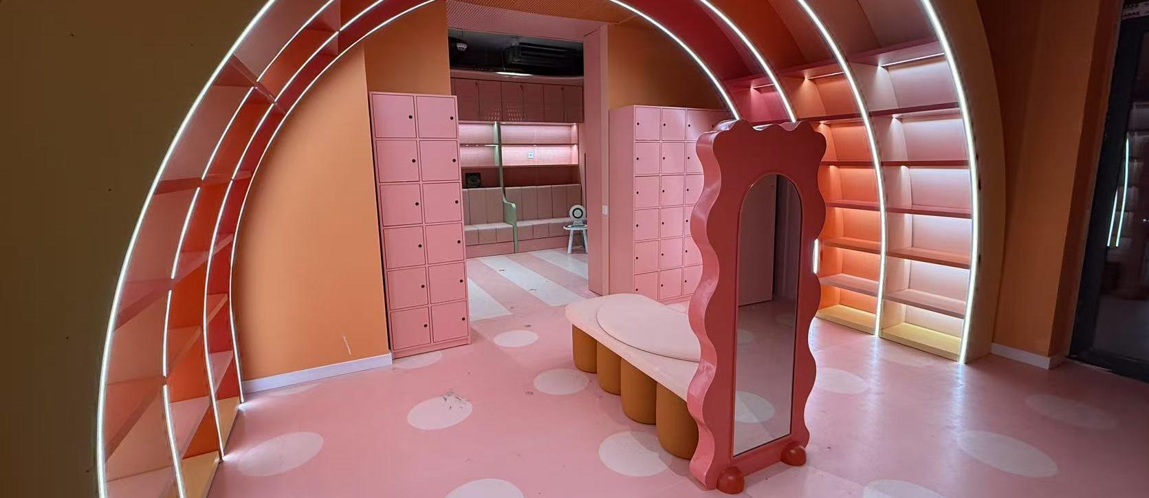 Pink arched passage in children retail space with rounded seating and soft lighting