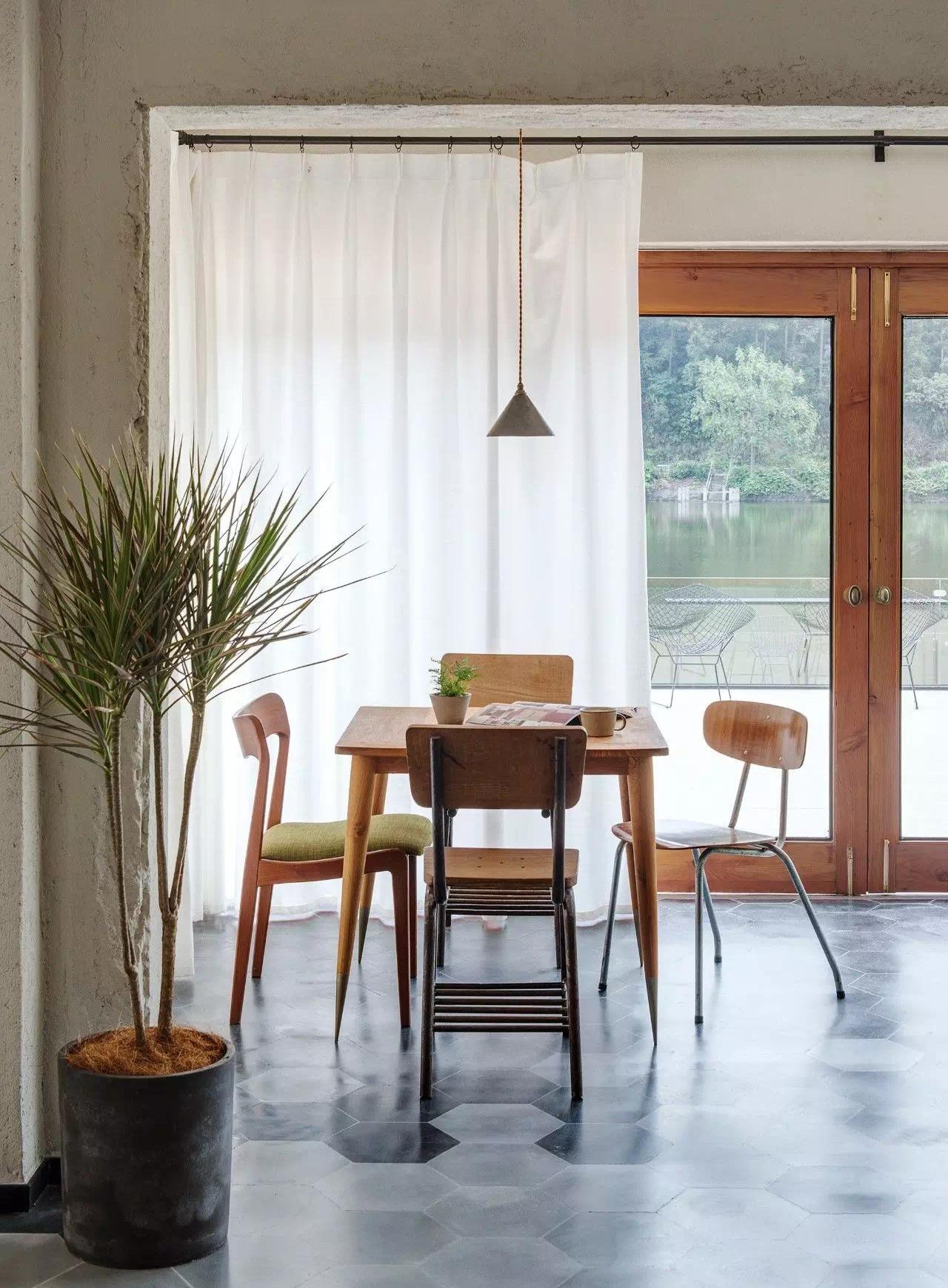 Wood dining table and chairs beside bright windows in boutique interior