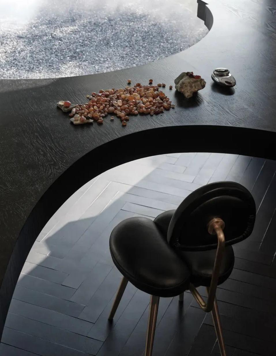 Wine bar lounge table with dark curved seating and refined material palette